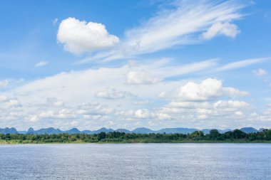 Nehir ve sirrus, kümülüs bulutları mavi gökyüzü arka planında.
