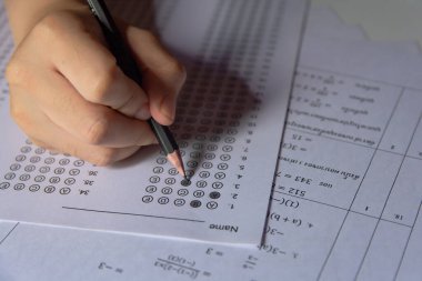 Öğrenciler, cevap kağıtları ve matematik soru kağıtları üzerinde seçilmiş kalemle yazı yazma seçeneğini el ele tutuyorlar. Sınav yapan öğrenciler. Okul çıkışı.