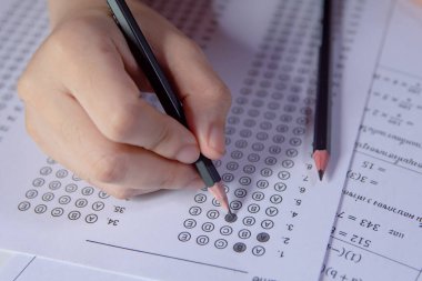 Öğrenciler, cevap kağıtları ve matematik soru kağıtları üzerinde seçilmiş kalemle yazı yazma seçeneğini el ele tutuyorlar. Sınav yapan öğrenciler. Okul çıkışı.