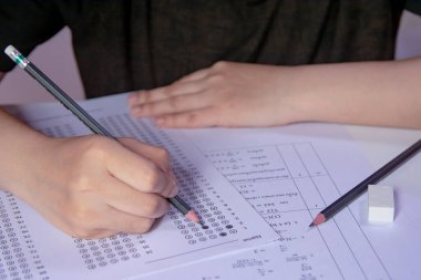 Öğrenciler, cevap kağıtları ve matematik soru kağıtları üzerinde seçilmiş kalemle yazı yazma seçeneğini el ele tutuyorlar. Sınav yapan öğrenciler. Okul çıkışı.