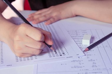 Öğrenciler, cevap kağıtları ve matematik soru kağıtları üzerinde seçilmiş kalemle yazı yazma seçeneğini el ele tutuyorlar. Sınav yapan öğrenciler. Okul çıkışı.