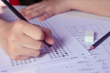 Öğrenciler, cevap kağıtları ve matematik soru kağıtları üzerinde seçilmiş kalemle yazı yazma seçeneğini el ele tutuyorlar. Sınav yapan öğrenciler. Okul çıkışı.