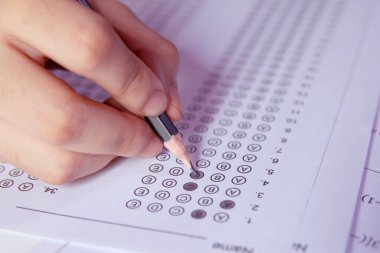Öğrenciler, cevap kağıtları ve matematik soru kağıtları üzerinde seçilmiş kalemle yazı yazma seçeneğini el ele tutuyorlar. Sınav yapan öğrenciler. Okul çıkışı.