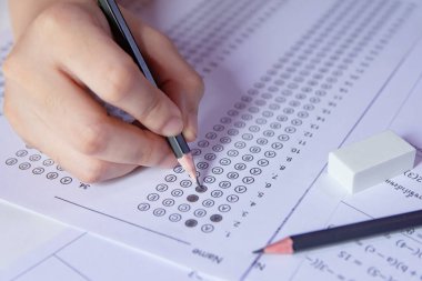 Öğrenciler, cevap kağıtları ve matematik soru kağıtları üzerinde seçilmiş kalemle yazı yazma seçeneğini el ele tutuyorlar. Sınav yapan öğrenciler. Okul çıkışı.