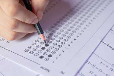 Öğrenciler, cevap kağıtları ve matematik soru kağıtları üzerinde seçilmiş kalemle yazı yazma seçeneğini el ele tutuyorlar. Sınav yapan öğrenciler. Okul çıkışı.