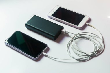 Beyaz masadaki elektrik bankasıyla çalışan akıllı telefon.