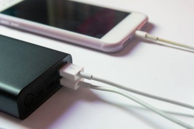 Beyaz masadaki elektrik bankasıyla çalışan akıllı telefon.