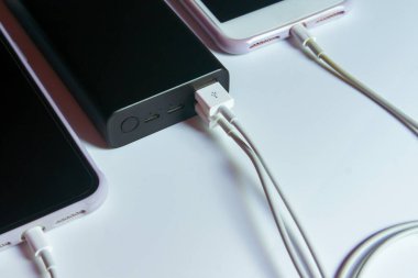 Beyaz masadaki elektrik bankasıyla çalışan akıllı telefon.