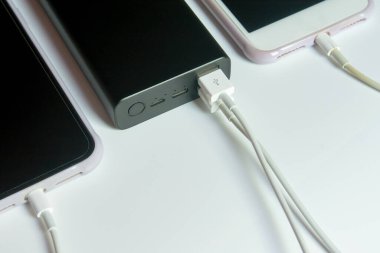 Beyaz masadaki elektrik bankasıyla çalışan akıllı telefon.