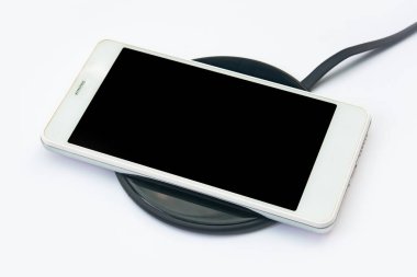 Beyaz arka planda kablosuz şarj cihazına akıllı telefon şarj oluyor. Kopyalama alanı için kırpma yolu olan siyah ekran veya boş ekran. Düz la