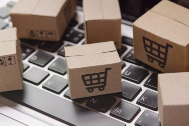 İnternetten alışveriş. Laptop klavyesinde alışveriş arabasının logosu olan karton kutu. İnternet 'te alışveriş servisi. Eve teslim etmeyi teklif ediyor