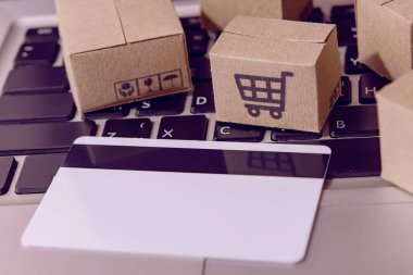 İnternetten alışveriş. Kredi kartı ve klavyede alışveriş arabasının logosu olan karton kutu. İnternet 'te alışveriş servisi. Eve teslim etmeyi teklif ediyor