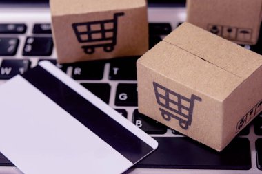 İnternetten alışveriş. Kredi kartı ve klavyede alışveriş arabasının logosu olan karton kutu. İnternet 'te alışveriş servisi. Eve teslim etmeyi teklif ediyor