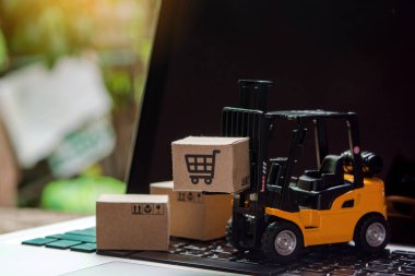 Çevrimiçi alışveriş için bilgisayar, lojistik ve teslimat hizmetlerinde kağıt karton veya paket içeren bir forklift yükleyicisi