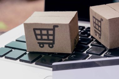 İnternetten alışveriş. Kredi kartı ve klavyede alışveriş arabasının logosu olan karton kutu. İnternet 'te alışveriş servisi. Eve teslimat teklif ediyor