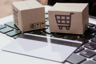 İnternetten alışveriş. Kredi kartı ve klavyede alışveriş arabasının logosu olan karton kutu. İnternet 'te alışveriş servisi. Eve teslimat teklif ediyor