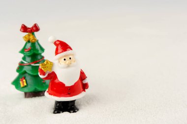 Mutlu Noeller ve mutlu yıllar konsepti. Tatlı noel baba figürü ve karlar üzerinde fotokopi alanı olan ağaç