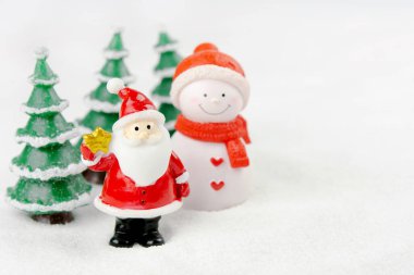 Mutlu Noeller ve mutlu yıllar konsepti. Şirin Noel Baba, kardan adam figürü ve kopyalanmış karlı ağaç.