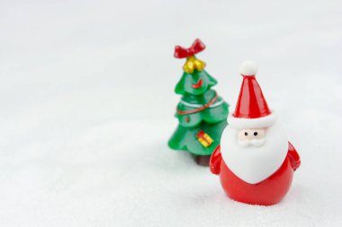 Mutlu Noeller ve mutlu yıllar konsepti. Tatlı noel baba figürü ve karlar üzerinde fotokopi alanı olan ağaç