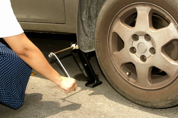Kadın bir lastik değiştirmek için bir makas jack kullanın