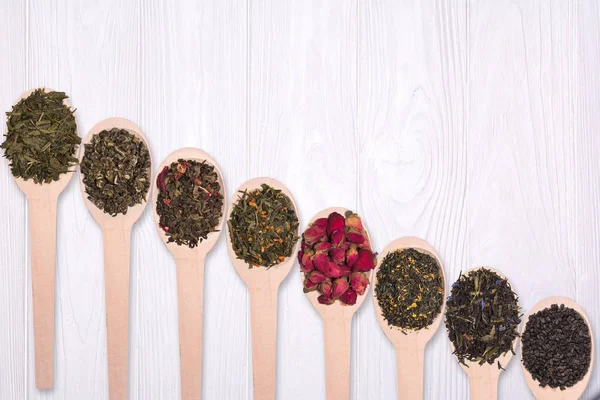 Tahta kaşık kuru bitkisel çayların beyaz bir arka plan üzerinde ayarlayın. Yukarıdan görüntülemek.