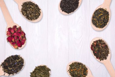 Çerçeve, beyaz zemin üzerine tahta kaşık kuru bitkisel çaylar