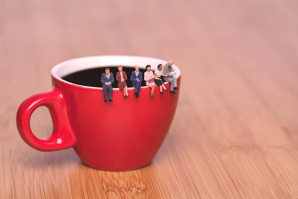 Creative concept about drinking coffee and waiting. Miniature people on the cup — Stock Photo, Image