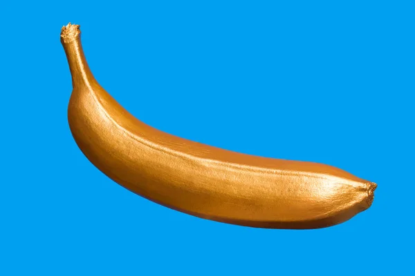 Gyllene banan på en blå bakgrund. Kreativa koncept med frukt. — Stockfoto