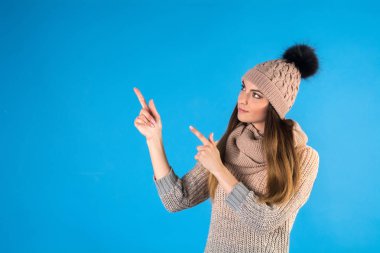 Kız sıcak kazak, atkı ve şapka mavi bir arka plan üzerinde