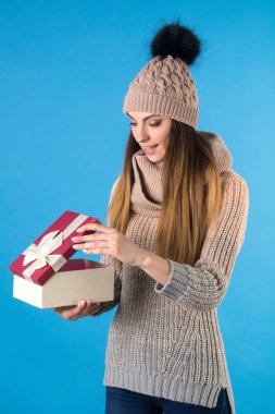 Kız bir örme sıcak kazak ve bir hediye kutusu ile şapka giymiş.