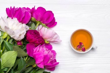 Bir fincan çay ve peonies çiçek beyaz ahşap zemin üzerinde