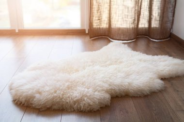 Sheep skin on the laminate floor in the room. Cozy place near the window. Sunny day. clipart