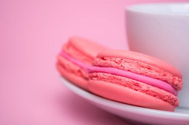 Pembe arka planda beyaz bir daire içinde iki pembe Macaron kurabiye