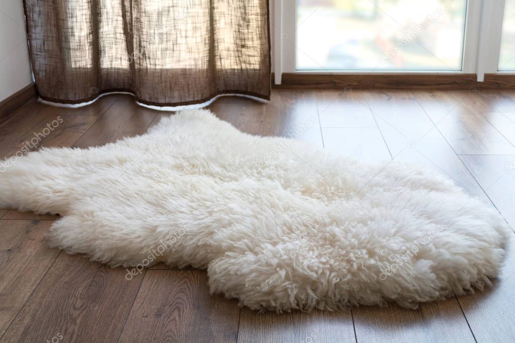 Sheep skin on the laminate floor in the room. Cozy place near the window.