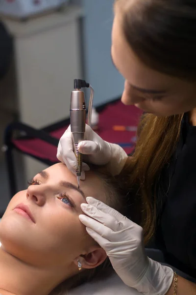 Permanent eyebrow makeup. Cosmetologist applying tattooing of eyebrows.
