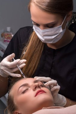 Kadın yüzüne botulinyum enjekte ediliyor.