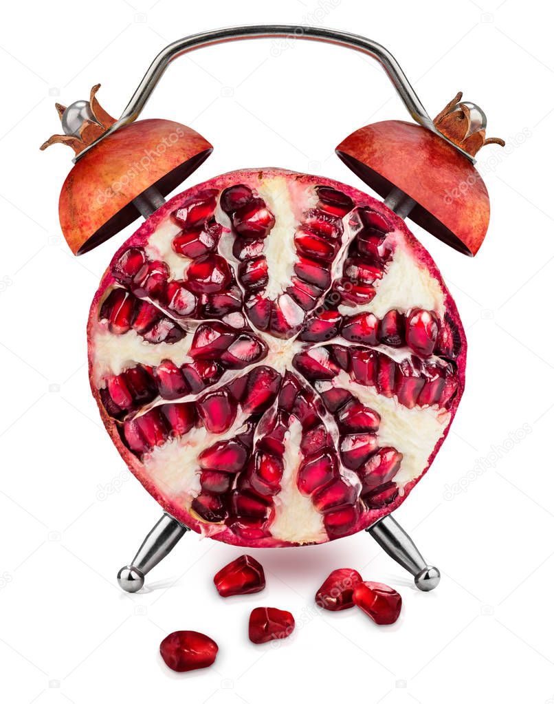 Halved pomegranate, with few scattered seeds, as an alarm clock on a white background. Healthy time concept.