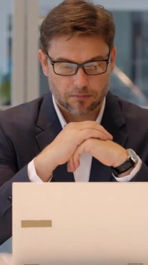 Kendini işine adamış profesyonel bir adam modern ve şık bir ofis ortamında dizüstü bilgisayarına odaklanmış, tamamen meşgul.