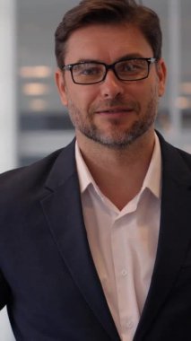 Ofiste gözlüklerle poz veren, modern bir çalışma alanı sergileyen kendine güvenen bir iş adamı..