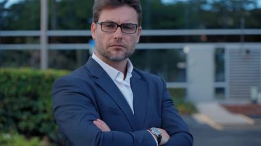 Resmi takım elbiseli şirket yöneticisi kameraya güvenle bakıyor. Erkek yönetici liderlik, otorite, mali başarı, şirket büyümesi ve ticari kararlılığı temsil eder.