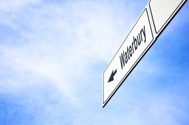 White signboard with an arrow pointing left towards Waterbury, Connecticut, USA, against a hazy blue sky in a concept of travel, navigation and direction. Path included for the signboard clipart