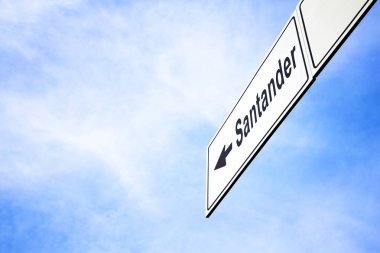Bir ok işaret ile beyaz tabela Santander, İspanya doğru seyahat, gezinti ve yön kavramı puslu bir mavi gökyüzünde karşı yaptı. Tabela için yola