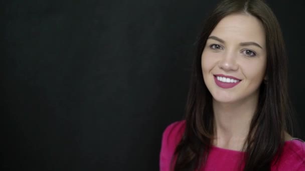 Mujer joven sonriendo al fondo negro — Vídeos de Stock