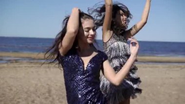 İki genç kadın elbiseleri plajda dans