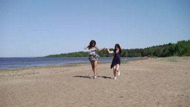 Çalışan ve elbiseler sahilde dans iki genç kadın