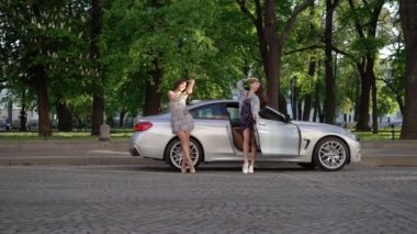 İki genç kadın lüks spor otomobil bir şehirde yakınındaki poz