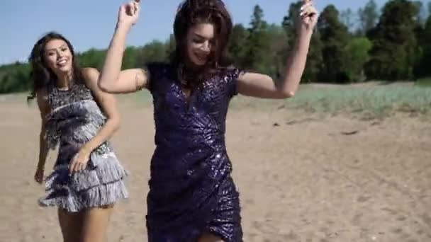 Dvě mladé ženy tančí na pláži v šatech — Stock video