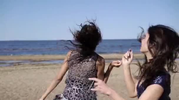 Duas jovens dançando na praia em vestidos — Vídeo de Stock