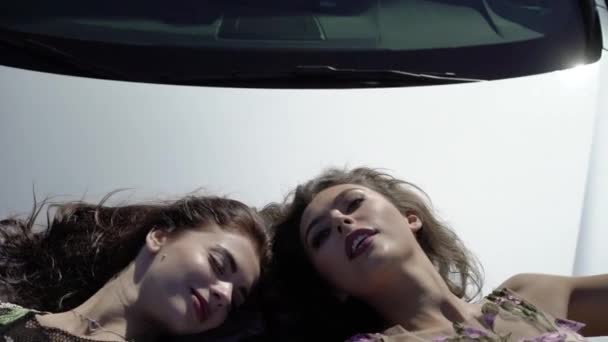 Dos jóvenes posando en el capó del coche — Vídeos de Stock