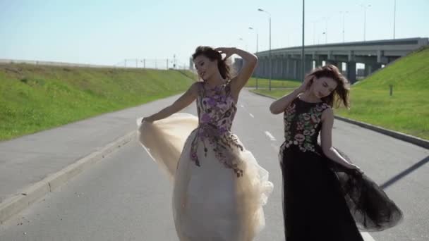 Две молодые женщины позируют на дороге — стоковое видео